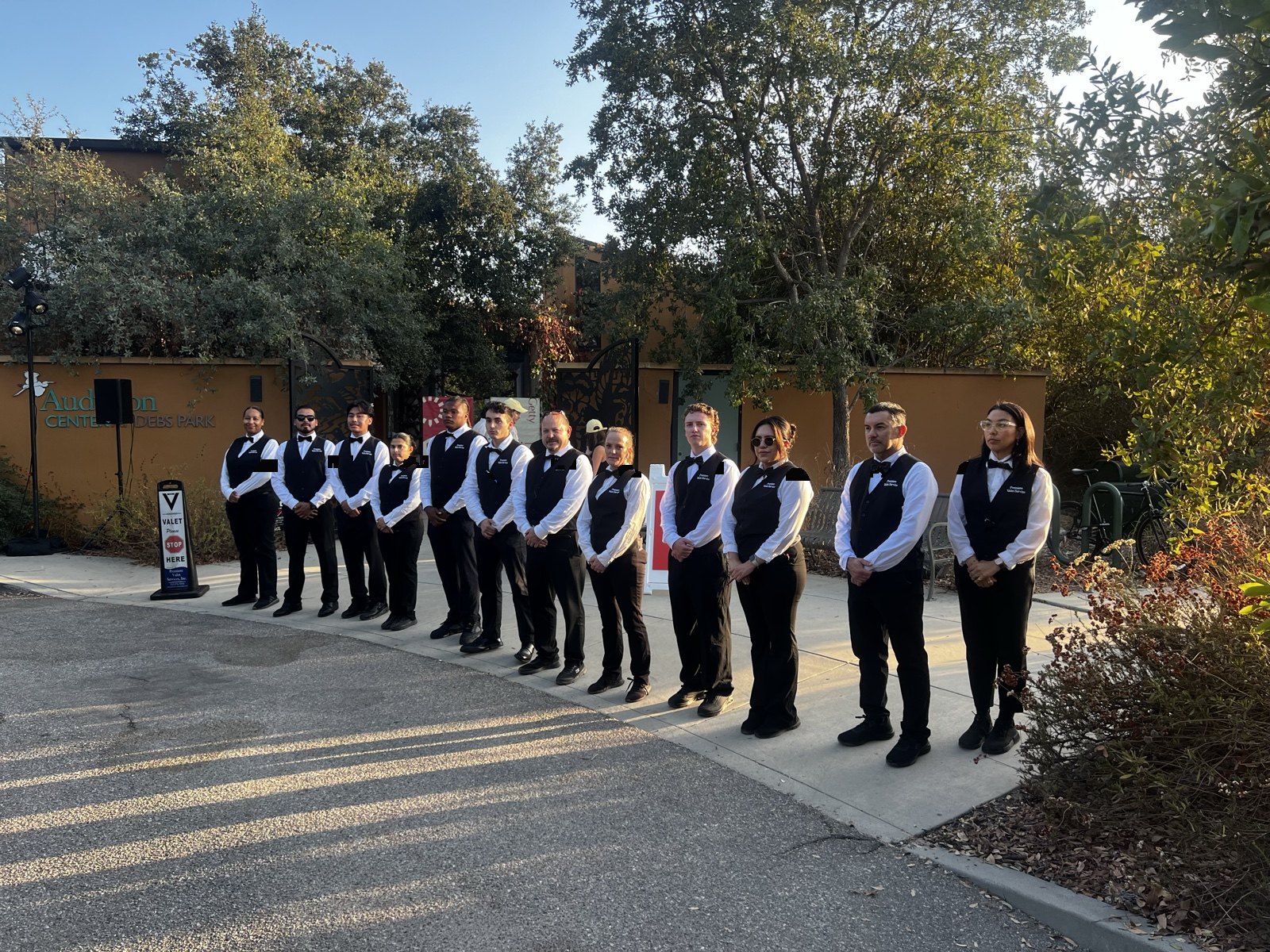 Valet attendants in black vests and bow ties lined up for event arrival service